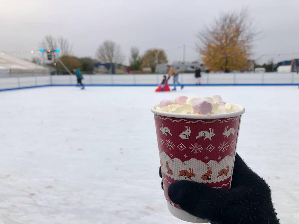Spectator holding hot chocolate with marshmallows at Avon Valley Festive  Ice Rink in Bristol
